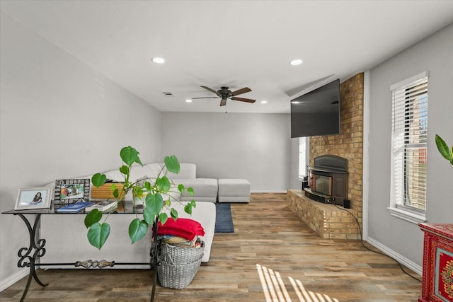 living room with ceiling fan, hardwood / wood-style flooring, a brick fireplace, and a wealth of natural light