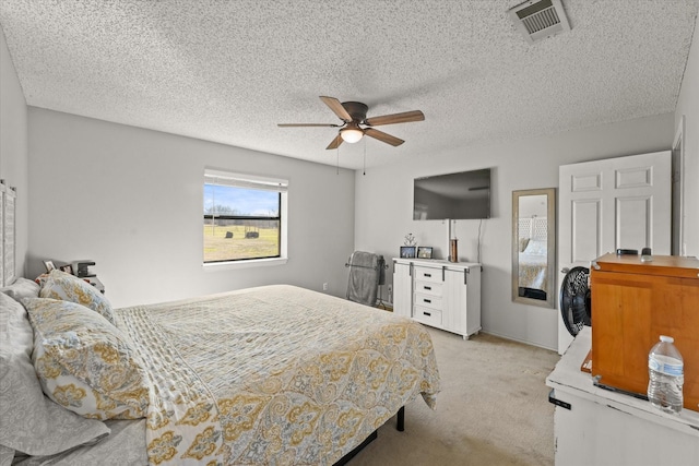 carpeted bedroom with ceiling fan and a textured ceiling