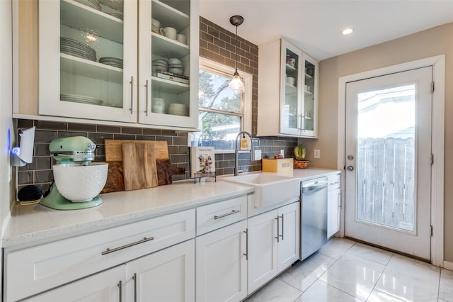 kitchen featuring decorative light fixtures, white cabinetry, sink, stainless steel dishwasher, and light stone countertops