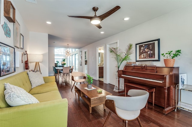 living room with ceiling fan with notable chandelier and dark hardwood / wood-style flooring