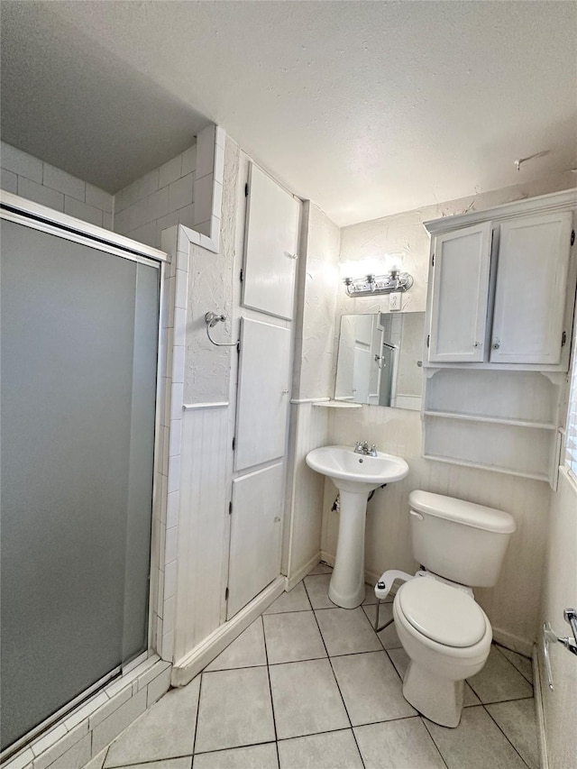 bathroom featuring toilet, tile patterned floors, a textured ceiling, and a shower with shower door