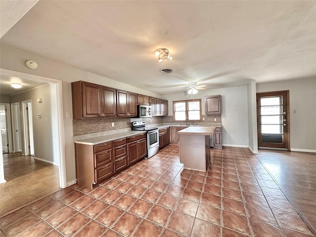 kitchen featuring appliances with stainless steel finishes, tasteful backsplash, sink, tile patterned flooring, and a center island