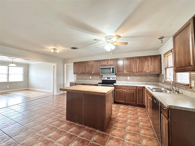 kitchen featuring a kitchen island, butcher block counters, sink, decorative backsplash, and stainless steel appliances