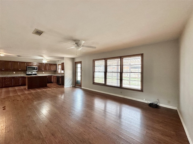 unfurnished living room featuring ceiling fan, dark hardwood / wood-style flooring, and a wealth of natural light