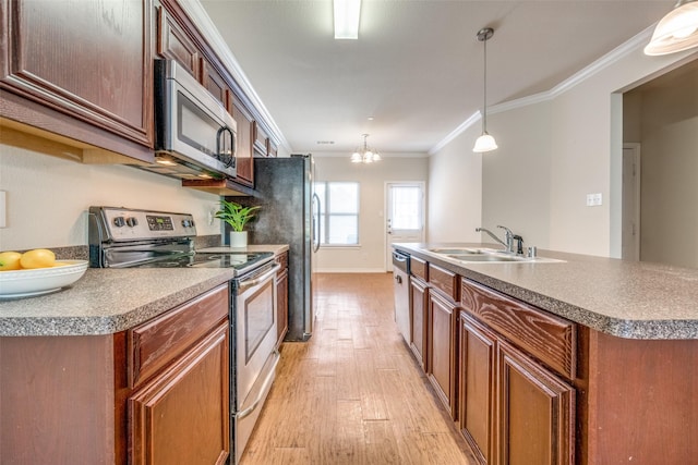 kitchen featuring sink, appliances with stainless steel finishes, hanging light fixtures, ornamental molding, and a center island with sink