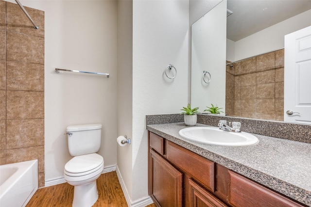 full bathroom featuring tiled shower / bath, vanity, toilet, and hardwood / wood-style floors