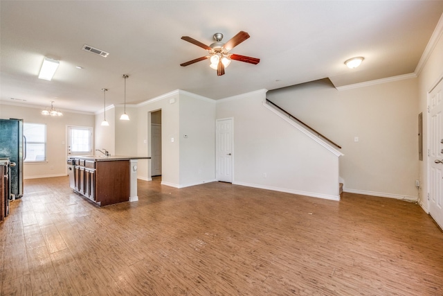 unfurnished living room featuring hardwood / wood-style flooring, crown molding, sink, and ceiling fan with notable chandelier