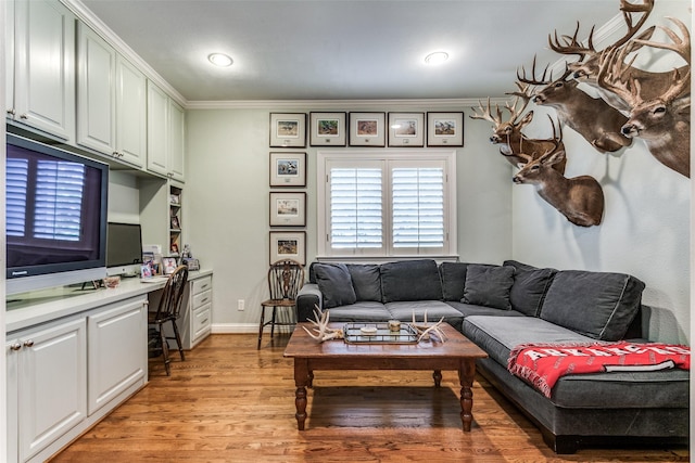 living room featuring crown molding, built in desk, and light hardwood / wood-style flooring