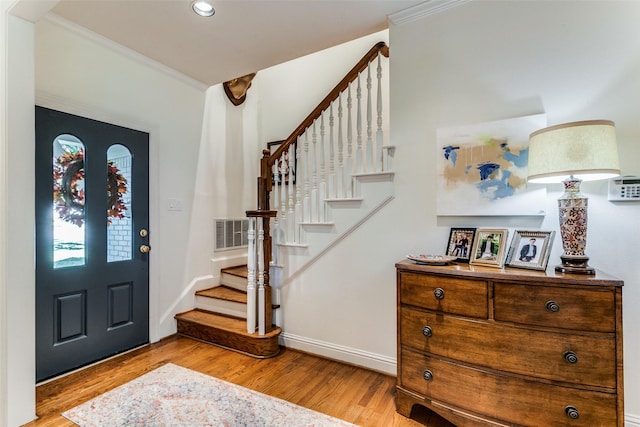 foyer entrance featuring crown molding and light wood-type flooring