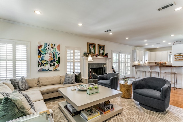 living room featuring ornamental molding, a fireplace, and light hardwood / wood-style floors