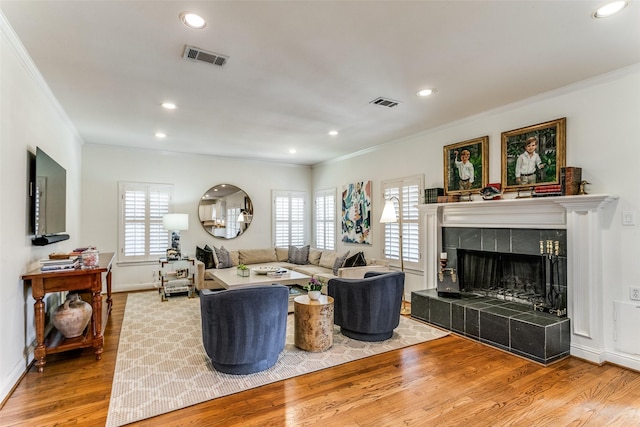 living room featuring a tile fireplace, hardwood / wood-style floors, and crown molding