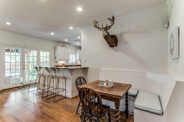 dining area with crown molding, light hardwood / wood-style flooring, and french doors