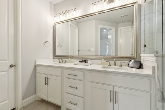 bathroom featuring a sink, visible vents, a marble finish shower, and double vanity