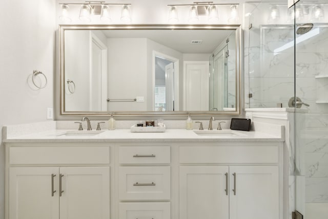 bathroom featuring a sink, a marble finish shower, visible vents, and double vanity