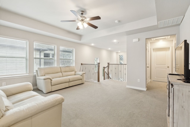 living area with visible vents, baseboards, light carpet, recessed lighting, and a raised ceiling