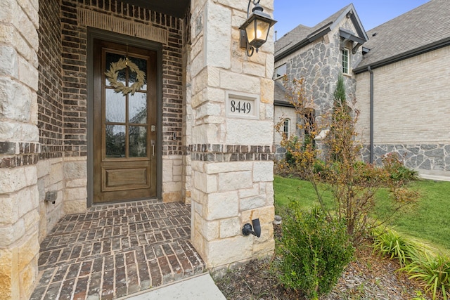 view of exterior entry with stone siding and brick siding