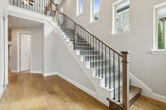 stairs with a high ceiling, wood finished floors, and baseboards