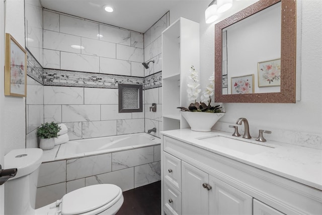 full bathroom featuring tiled shower / bath, vanity, and toilet