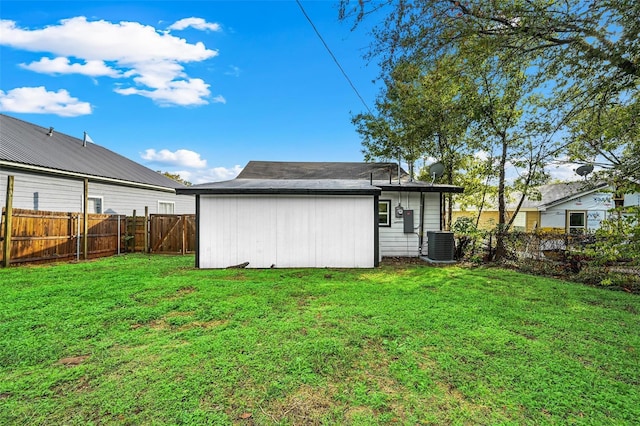 rear view of house featuring central AC and a lawn