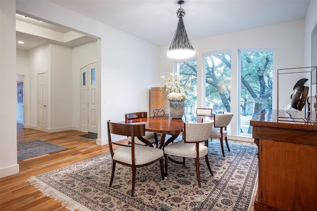 dining space with a wealth of natural light, an inviting chandelier, and light hardwood / wood-style flooring