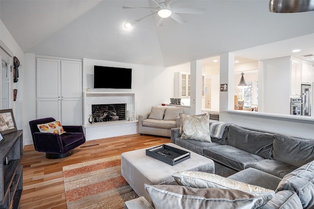 living room with ceiling fan, high vaulted ceiling, and light hardwood / wood-style floors