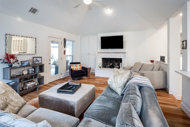 living room with light hardwood / wood-style flooring, vaulted ceiling, and ceiling fan