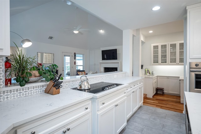 kitchen with white cabinetry, light stone counters, black electric cooktop, and stainless steel oven