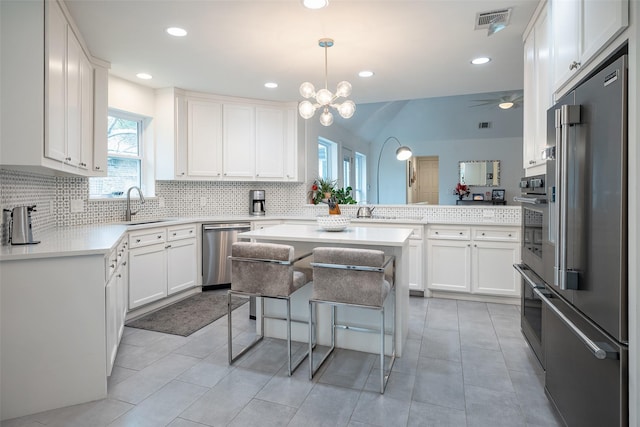 kitchen featuring appliances with stainless steel finishes, sink, white cabinets, a kitchen breakfast bar, and a center island