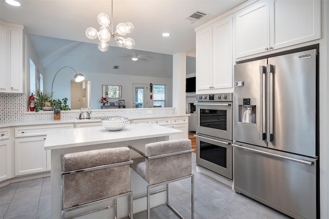 kitchen featuring a kitchen island, appliances with stainless steel finishes, white cabinets, and a kitchen breakfast bar