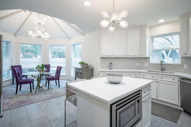 kitchen with pendant lighting, appliances with stainless steel finishes, a center island, white cabinets, and a chandelier