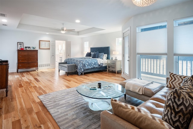 bedroom with ceiling fan, a raised ceiling, and light hardwood / wood-style flooring