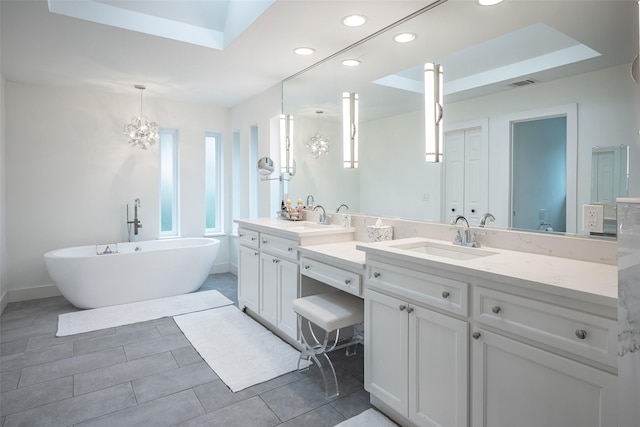 bathroom featuring tile patterned floors, a tub to relax in, a raised ceiling, and vanity