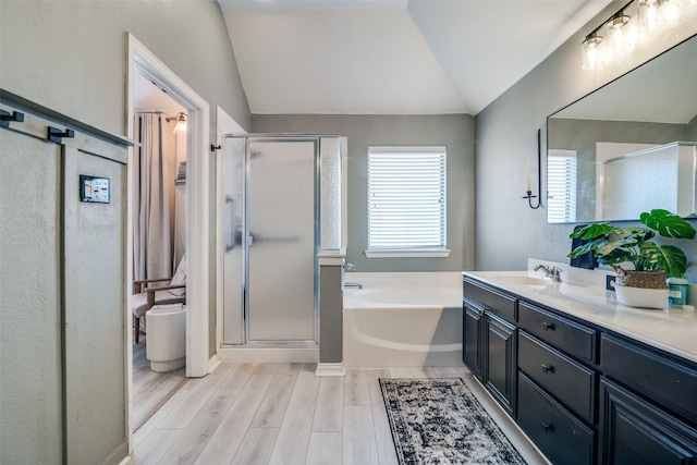 bathroom featuring vanity, hardwood / wood-style flooring, vaulted ceiling, and plus walk in shower