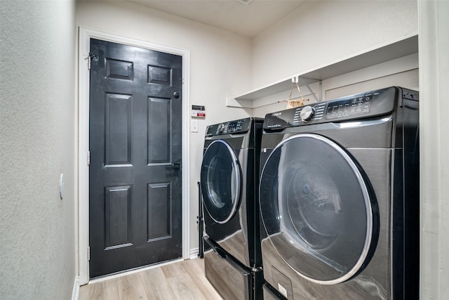 laundry room with light hardwood / wood-style flooring and washing machine and dryer