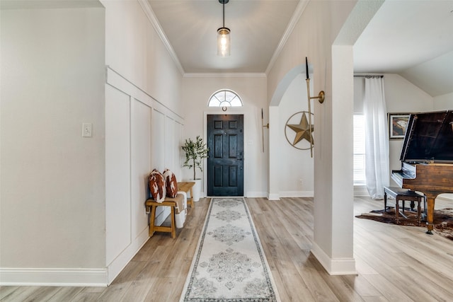 entryway with ornamental molding and light hardwood / wood-style flooring