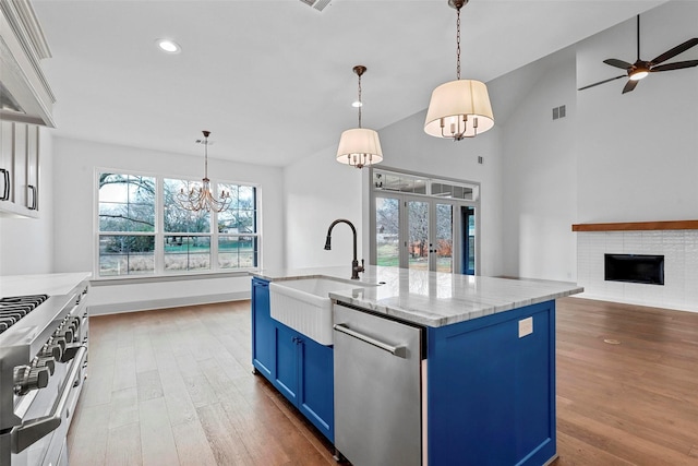 kitchen with french doors, decorative light fixtures, open floor plan, an island with sink, and blue cabinets