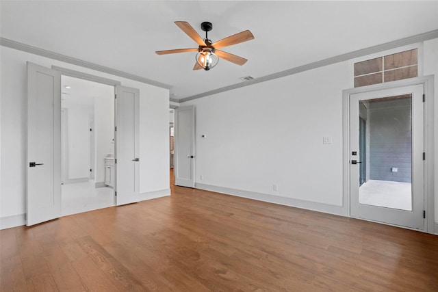 spare room with light wood finished floors, visible vents, ornamental molding, a ceiling fan, and baseboards