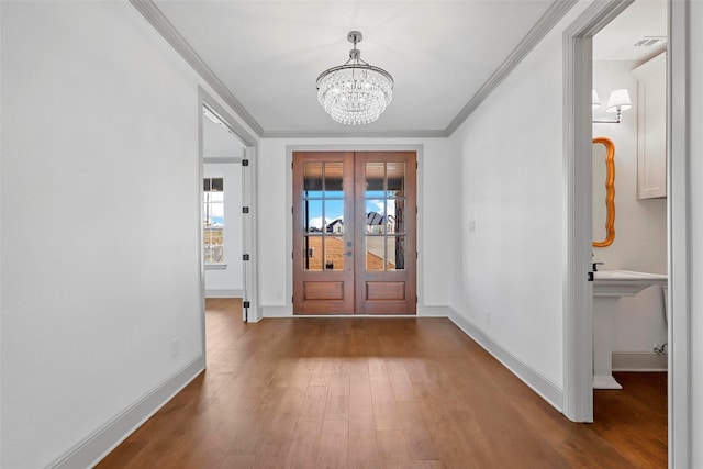 foyer entrance with baseboards, french doors, ornamental molding, dark wood finished floors, and an inviting chandelier