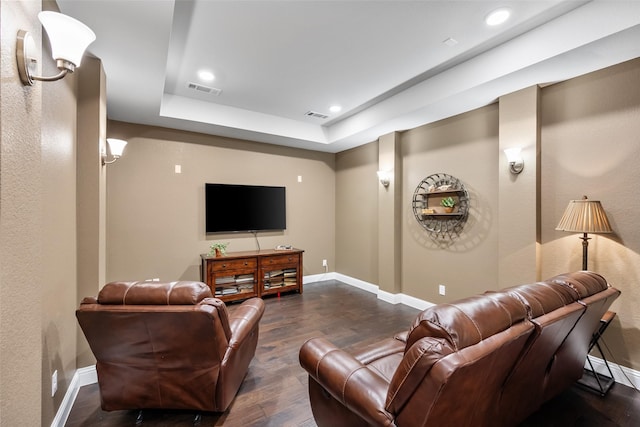 home theater with a raised ceiling and dark wood-type flooring