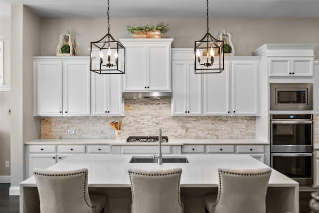 kitchen with white cabinetry, appliances with stainless steel finishes, and decorative light fixtures