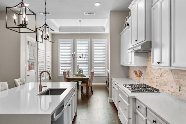 kitchen with pendant lighting, sink, appliances with stainless steel finishes, white cabinets, and a raised ceiling