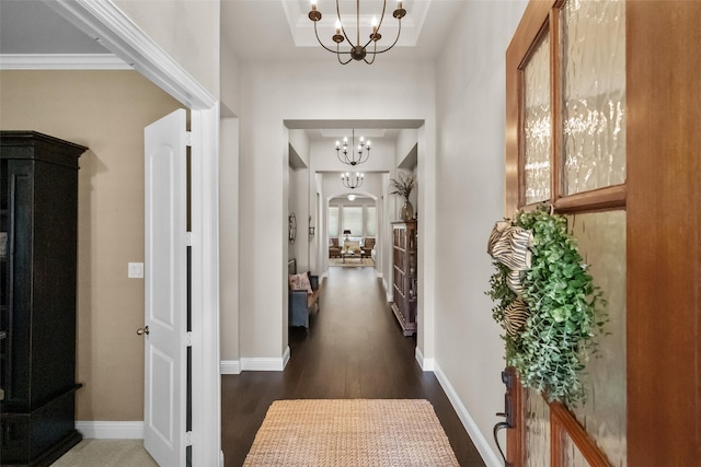 hall featuring a raised ceiling, dark hardwood / wood-style flooring, and a chandelier