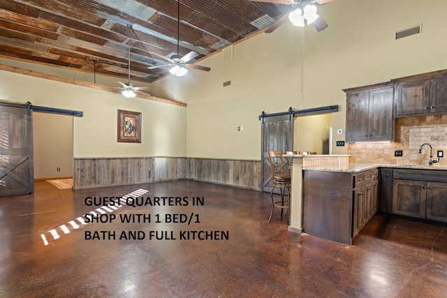 kitchen featuring appliances with stainless steel finishes, sink, a kitchen bar, light stone counters, and kitchen peninsula