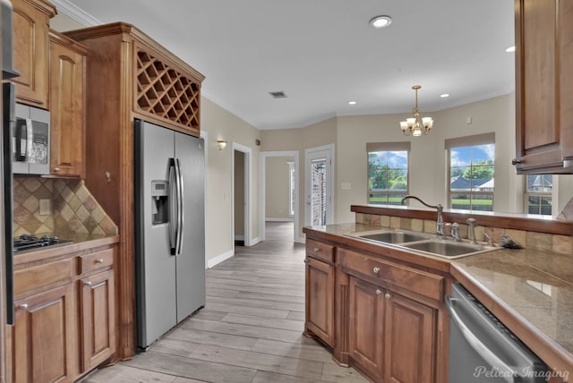 kitchen featuring sink, decorative light fixtures, light wood-type flooring, stainless steel appliances, and decorative backsplash