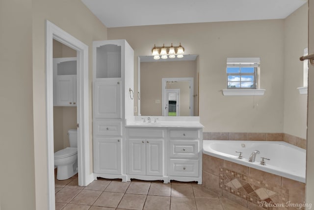 bathroom with tiled tub, vanity, tile patterned floors, and toilet