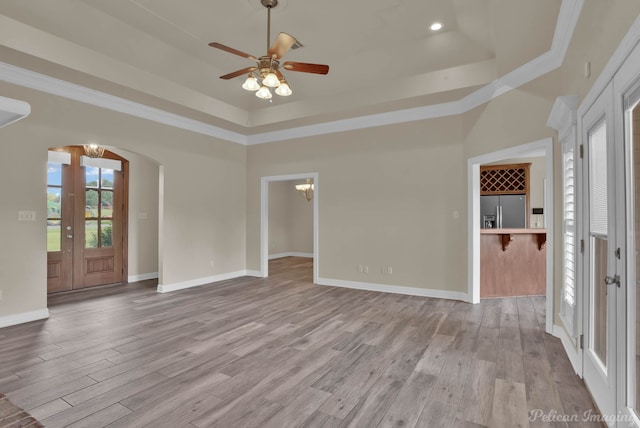 interior space featuring french doors, ornamental molding, a tray ceiling, and light hardwood / wood-style floors