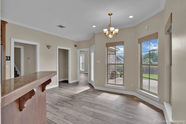 dining space with an inviting chandelier, crown molding, and light hardwood / wood-style flooring