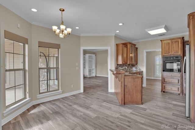 kitchen featuring light hardwood / wood-style flooring, stainless steel refrigerator, kitchen peninsula, black oven, and pendant lighting