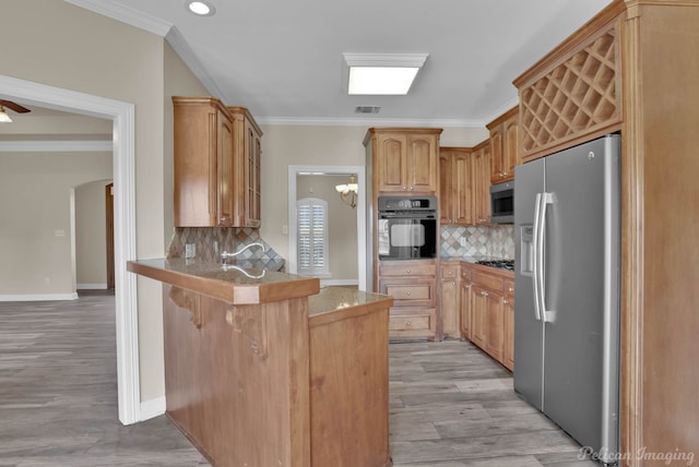 kitchen with appliances with stainless steel finishes, a kitchen breakfast bar, kitchen peninsula, crown molding, and light wood-type flooring