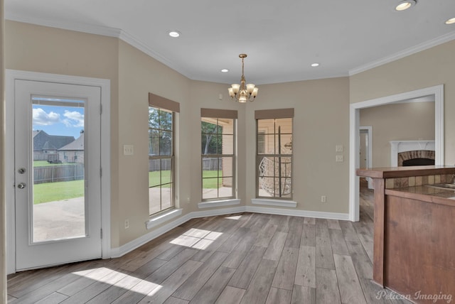 unfurnished dining area with ornamental molding, a healthy amount of sunlight, and light hardwood / wood-style flooring